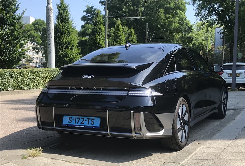 A Black Hyundai IONIQ six parked along the side of the road on a sunny day.