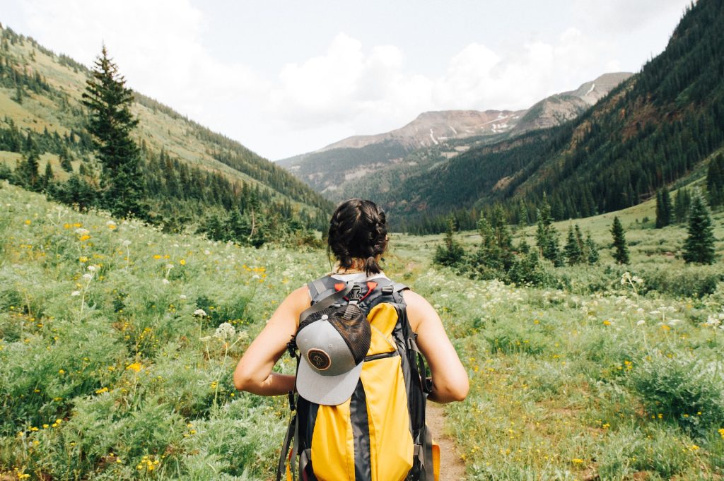 A man with a yellow backpack hiking through the mountains on a trail