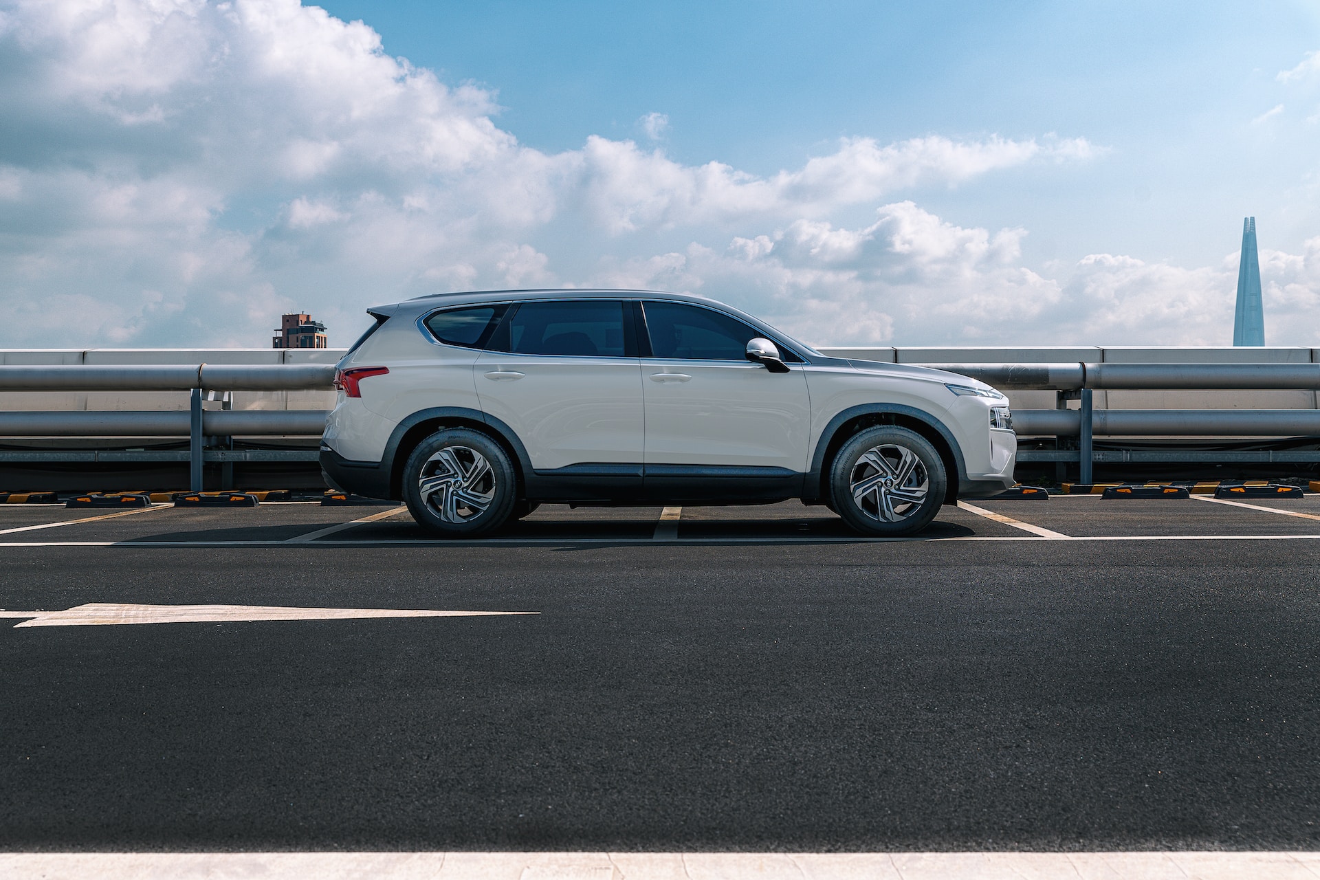 A white Hyundai parking in a parking lot on a sunny day in front of metal pipes
