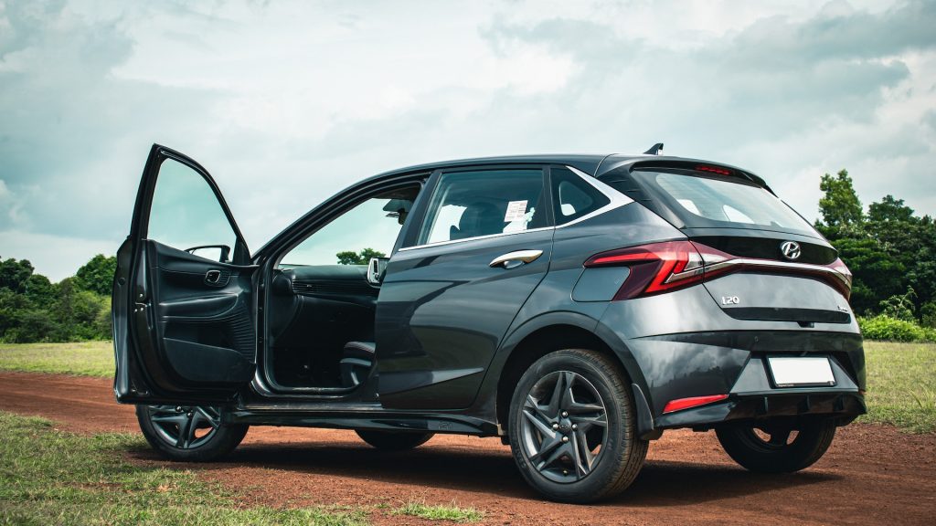 A Hyundai parked on a dirt road with the driver's seat door open.