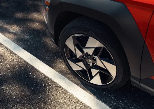 Red painted 2024 Hyundai Kona wheel tires with rims in parking space.