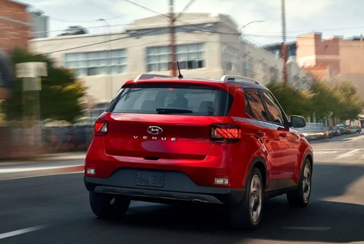 2025 Hyundai Venue in red paint driving through a city.